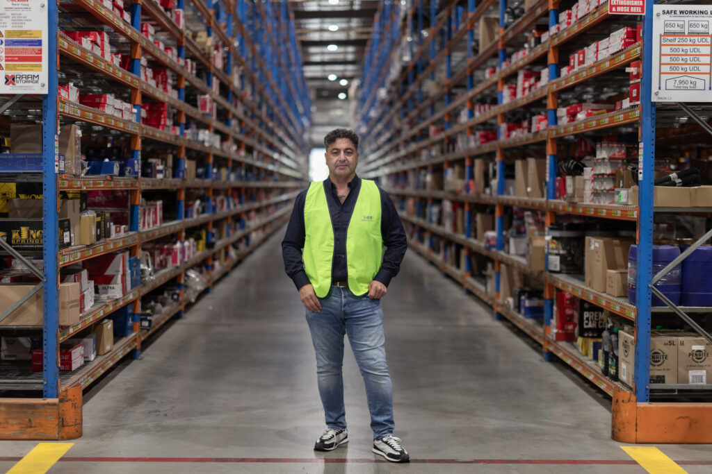 James Marroun stands confidently in a warehouse aisle, showcasing TLH Group's extensive inventory and commitment to quality.