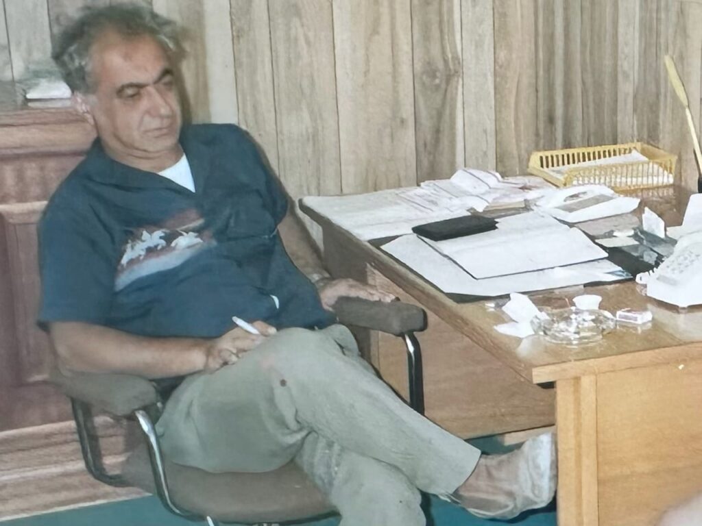 Maurice Marroun, father to James Marroun at his desk, surrounded by papers and office supplies.